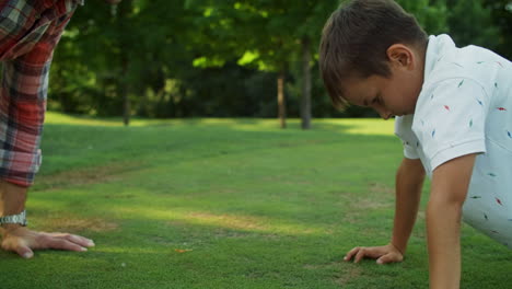 padre e hijo haciendo flexiones en el parque. hombre y niño practicando ejercicios de fitness