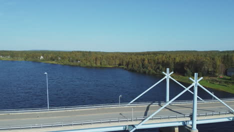 Blue-and-green-dominate-nature-scene,-aerial-descends-to-river-bridge