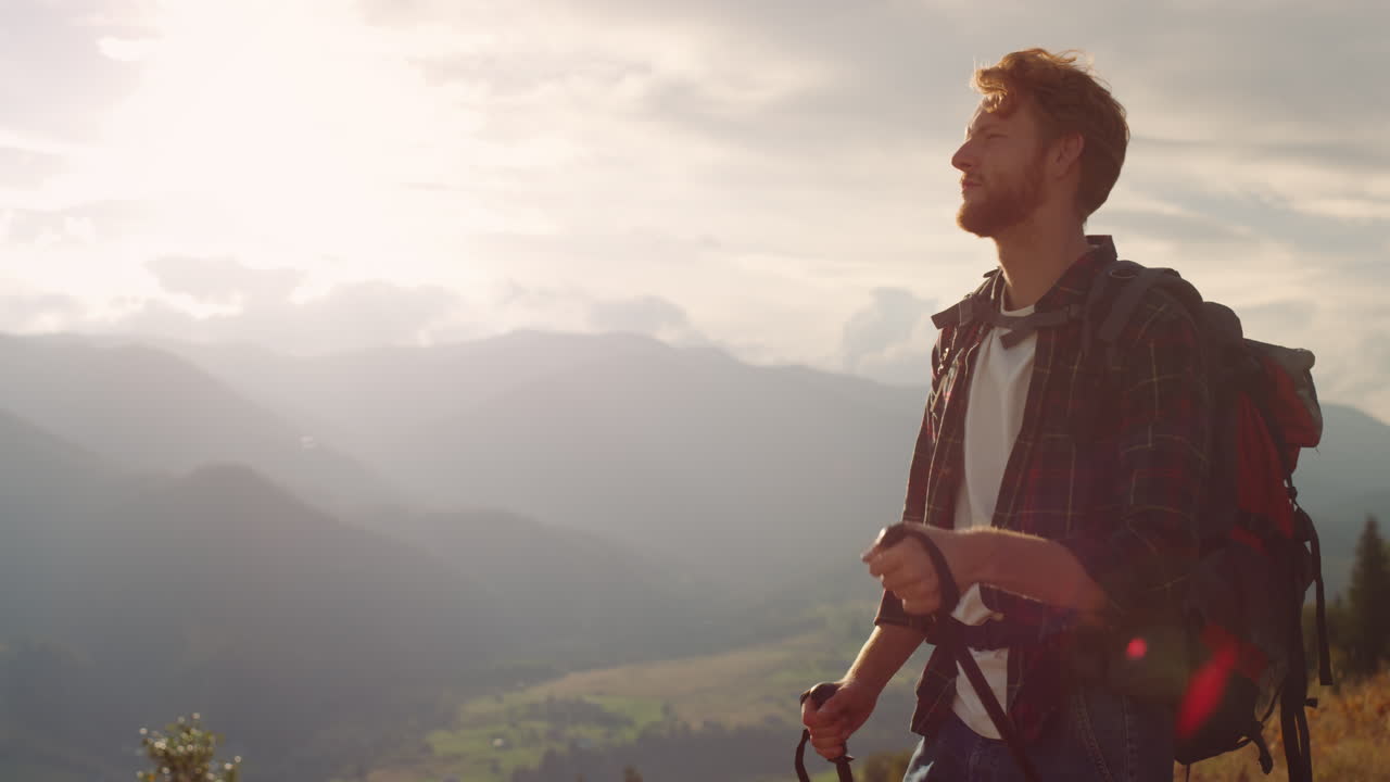 Escursionista energico cammina nella natura su un paesaggio montano. Un hipster usa i bastoncini da trekking.