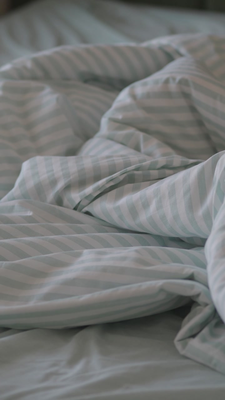 Empty Rumpled Bed with Green and White Striped Duvet
