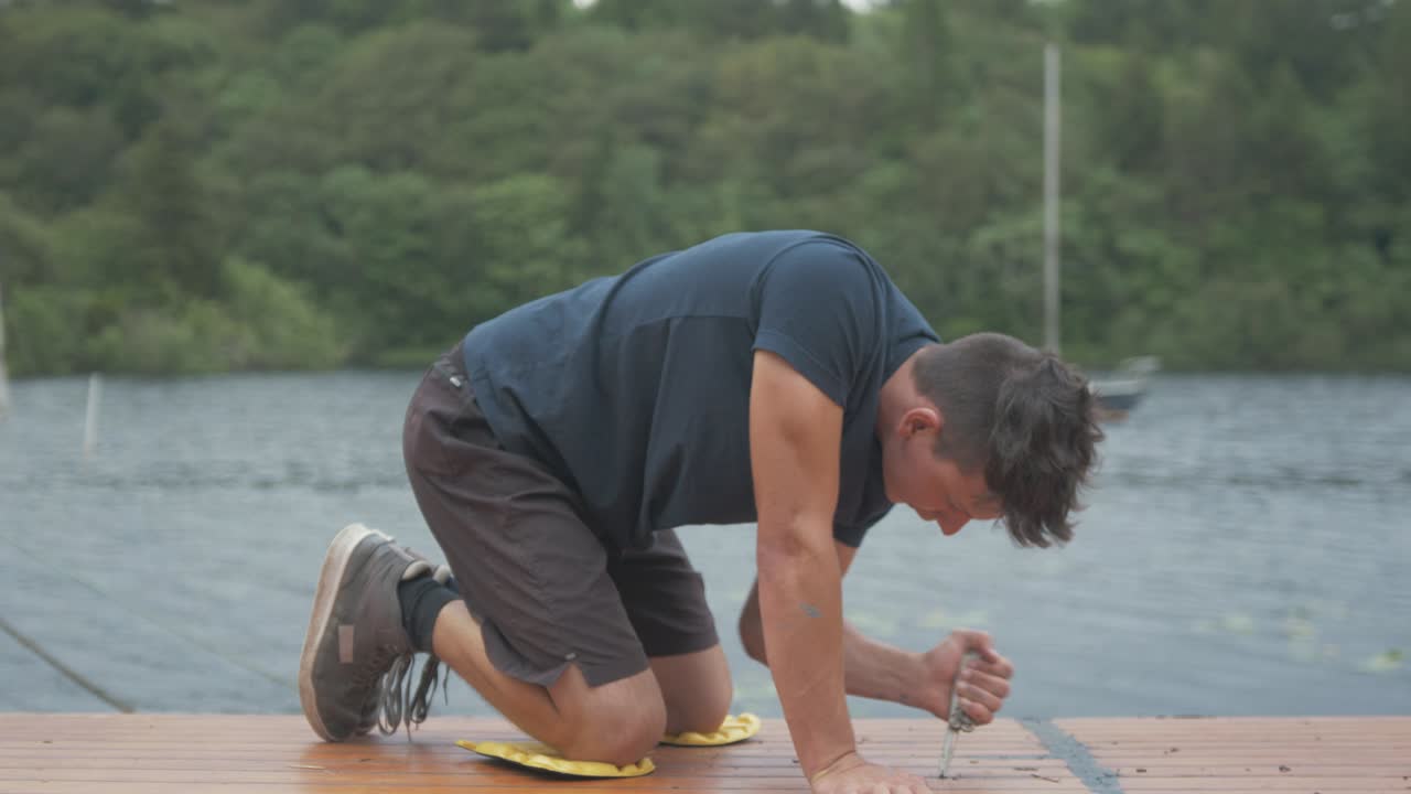 판자 사이의 오래된 실란트를 긁어내기 위해 칼을 사용하는 젊은 엄마