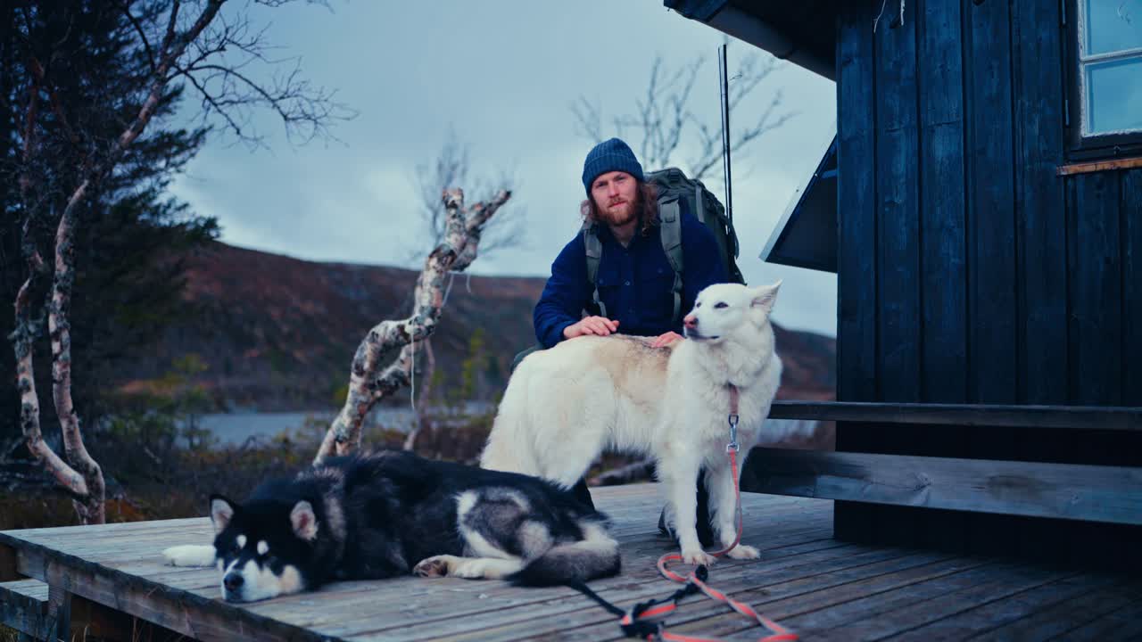Man With His Pet Dogs Resting Outside A Cabin In Åfjord, Norway - Static Shot