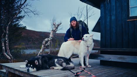man with his pet dogs resting outside a cabin in åfjord, norway - static shot