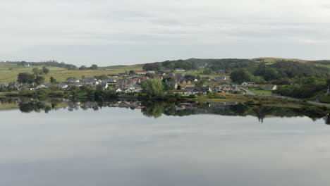 Eine-Luftaufnahme-Des-Dorfes-Lairg,-Das-Sich-An-Einem-Ruhigen-Sommermorgen-Im-Flussschien-Spiegelt