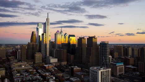 aerial pull back timelapse of the philadelphia skyline during a colorful sunset showcasing the tall, advanced buildings and urban development