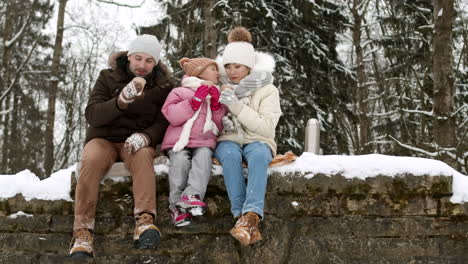 family enjoying hot drinks in the snow