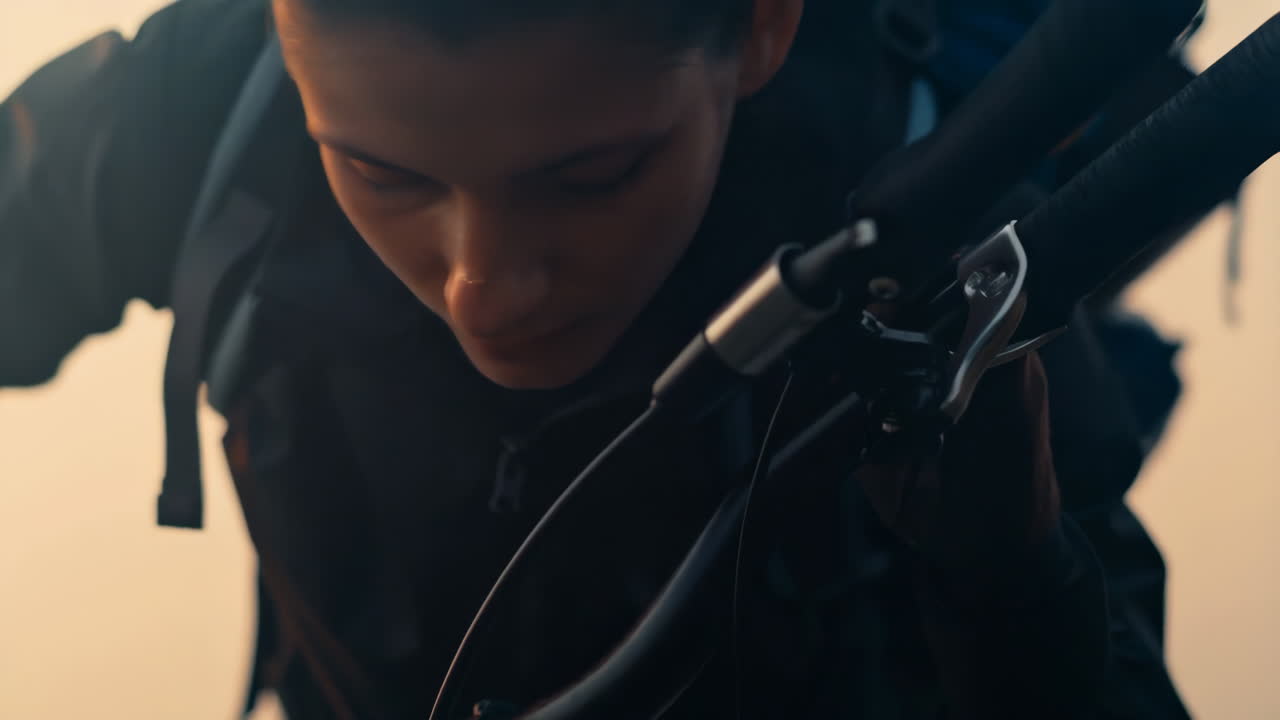 A young woman with a backpack preparing her bicycle at sunrise or sunset