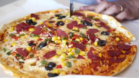 persona cortando una pizza