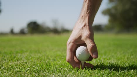 caucasian male golfer positioning a golf ball on a tee