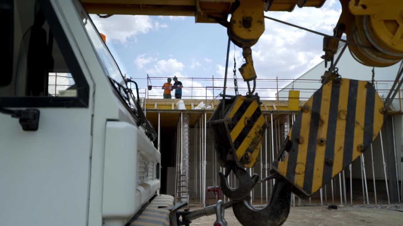 Grande gru con struttura in costruzione e operai edili sullo sfondo