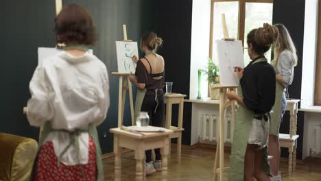 group of students painting at art lesson in studio in slowmo