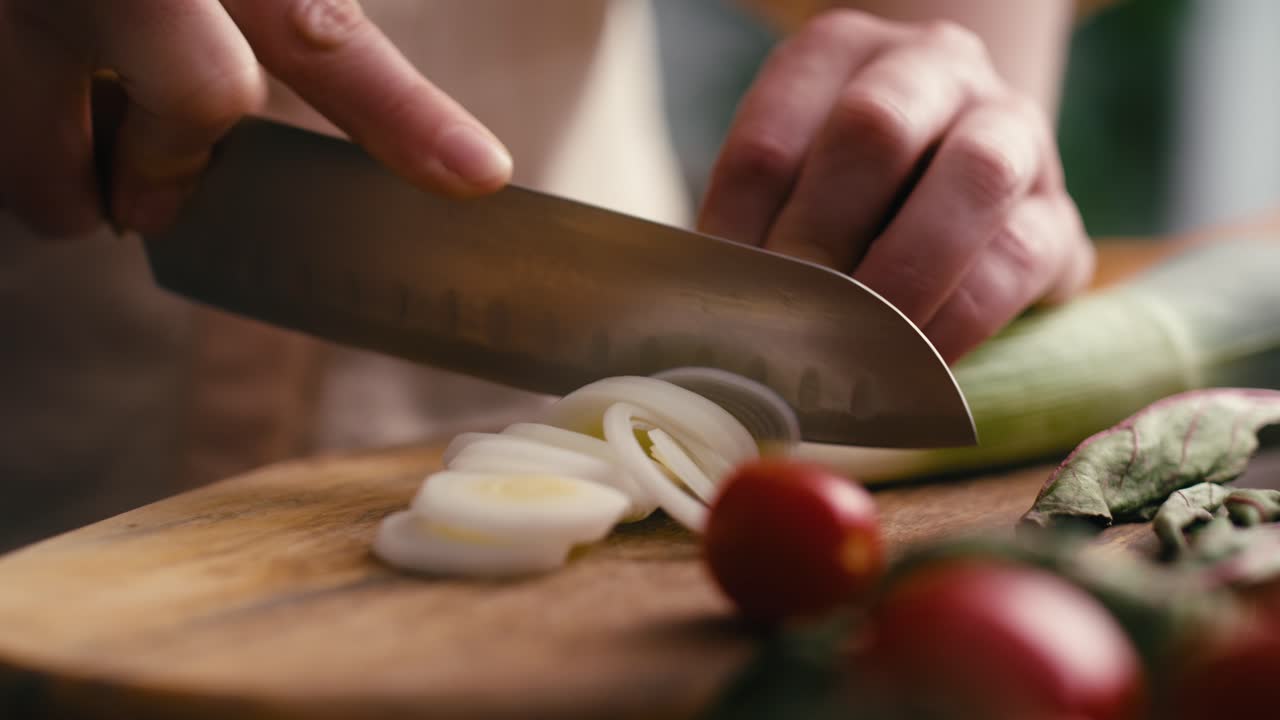 cerca de las manos de la mujer cortando puerro en la cocina.