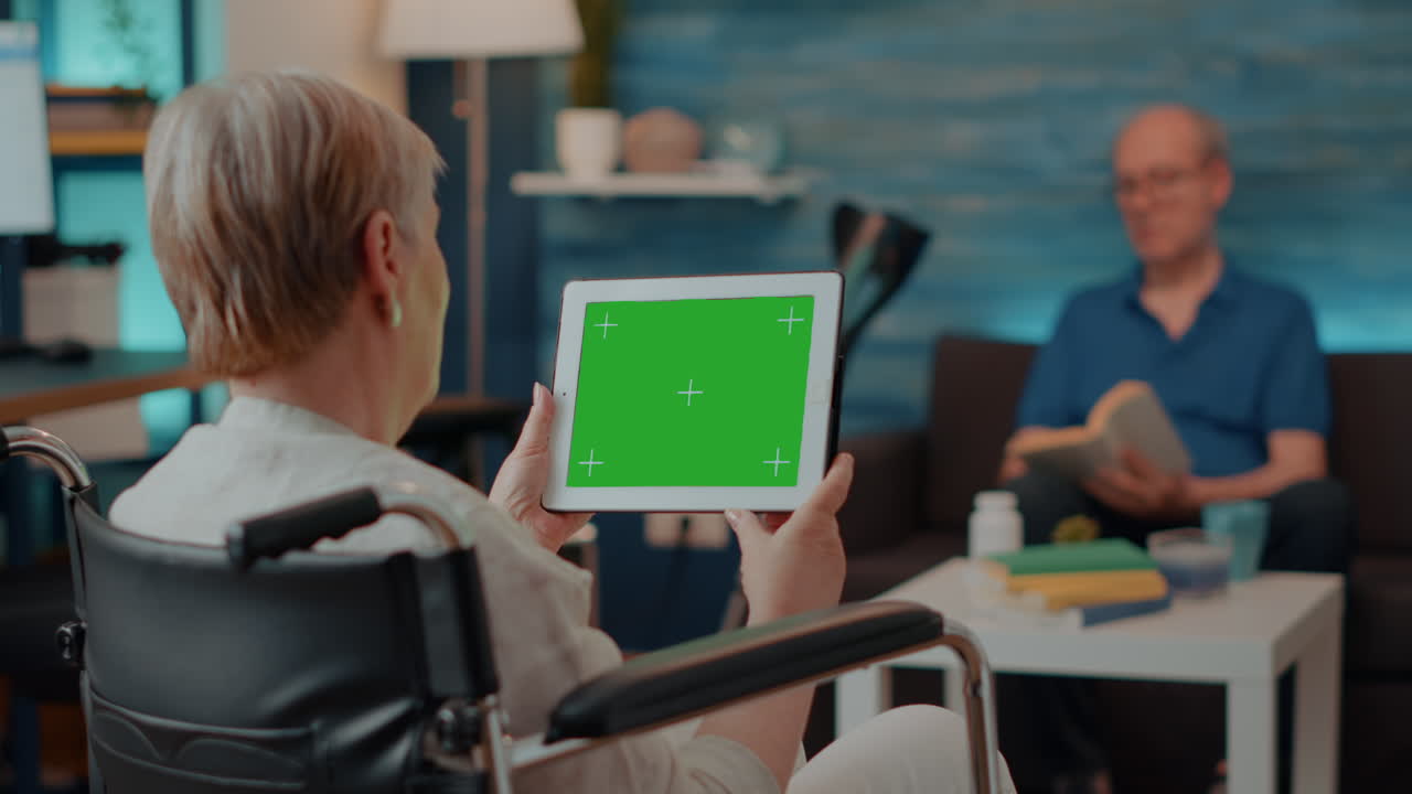 Senior woman using tablet with green screen in wheelchair