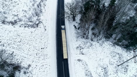 Camión-Largo-Aislado-Cargado-Con-Madera-Que-Conduce-Lentamente-A-Lo-Largo-De-Un-Camino-Nevado