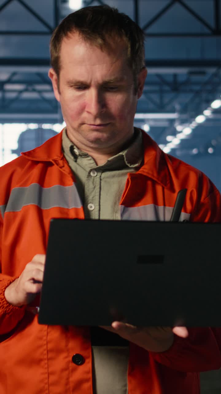 Vertical Video Worker walking in manufacturing facility handling equipment for fabrication tasks