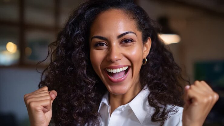 Festosa celebrazione: una donna con capelli ricci mostra la sua emozione e felicità attraverso gesti entusiasti e un sorriso affascinante in un ambiente dinamico