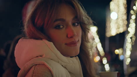 woman drinking mulled wine at night christmas fair closeup. girl festive market