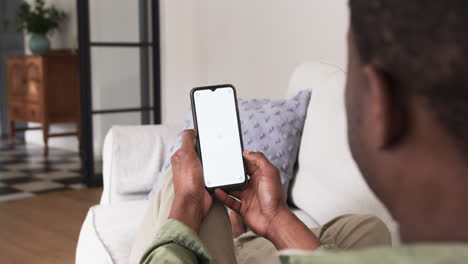 man using smartphone while relaxing on cozy couch at home, copy space