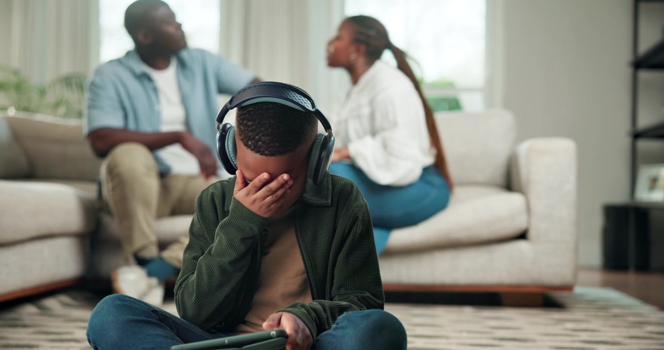 Young Boy Wearing Headphones Ignoring Parents Arguing in Background