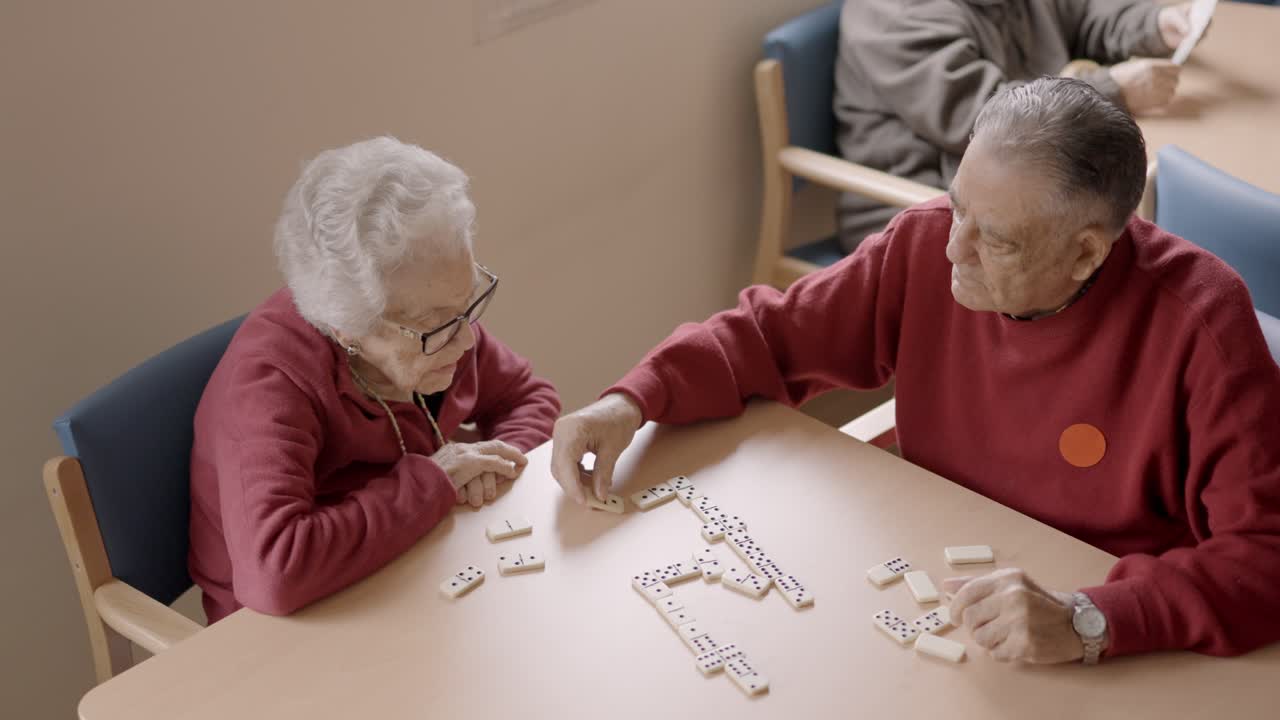 Senior man playing dominoes with old friend in a geriatric