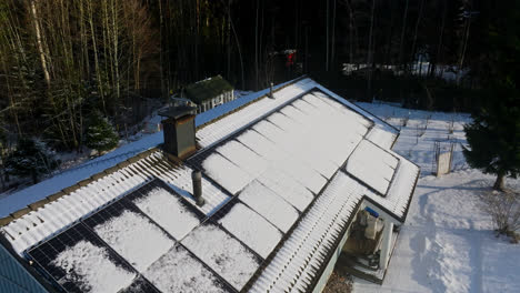 aerial view rising around a melting roof with photovoltaic cells, winter day