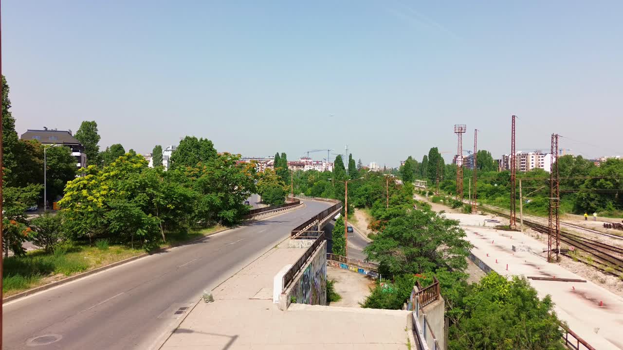 volando sobre una carretera de varias capas, con escaleras y vías ferroviarias en el lado en un día soleado