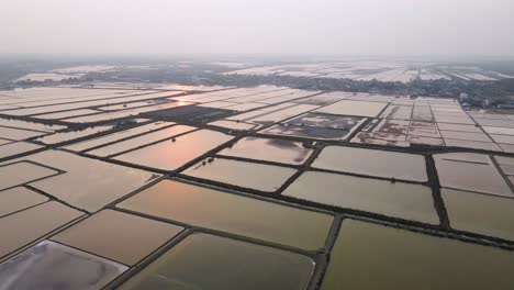 Sonnenuntergang-über-Meersalzverdunstungsteichen,-Die-Mit-Flachem-Wasser-Gefüllt-Sind