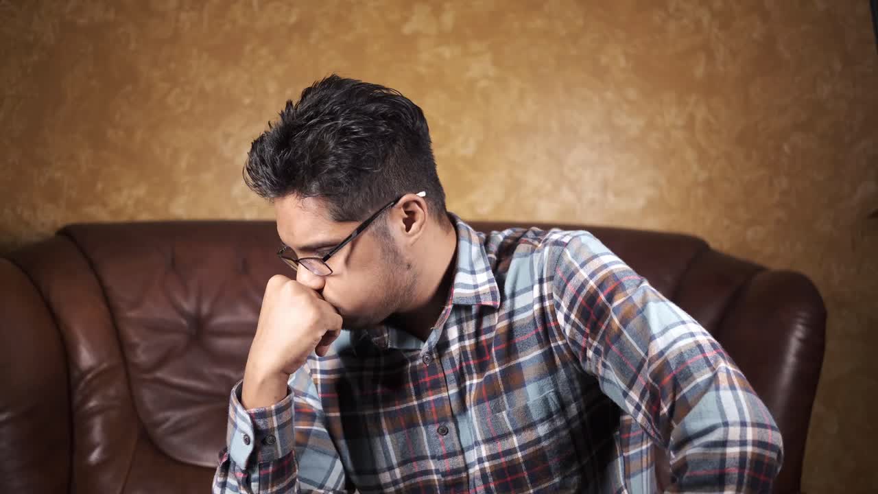 소파 에 앉아서 사려 깊은 생각 을 하고 있는 젊은 남자