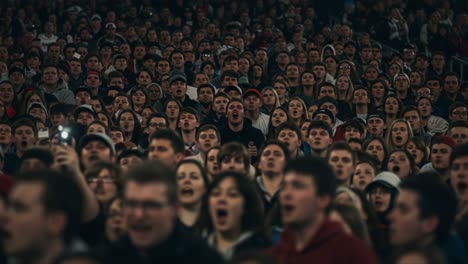 an enthusiastic crowd of fans expressing passion and emotion in a packed stadium, capturing the energy of the event as they cheer and support their team