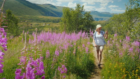 an active woman walks through a beautiful valley among flowering flowers against the backdrop of mou