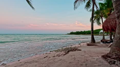 Hyperlapse-of-Tulum-Mexico-and-the-Caribbean-Sea-with-palm-tree-swaying-in-the-breeze-and-Timelapse-of-waves-breaking-on-the-shore-at-sunset