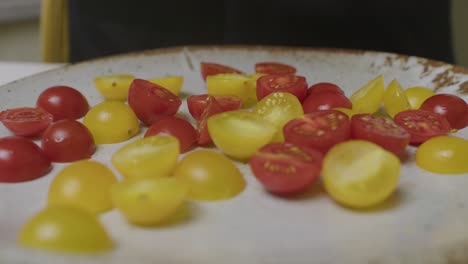 los tomates de cereza en rodajas caen en un plato grande