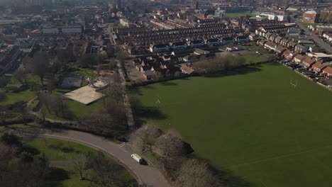 4K-aerial-view-of-a-residencial-area-in-taunton-Somerset,-United-Kingdom,-drone-moving-to-the-right-and-showing-the-open-field,-buildings-roofs-and-street