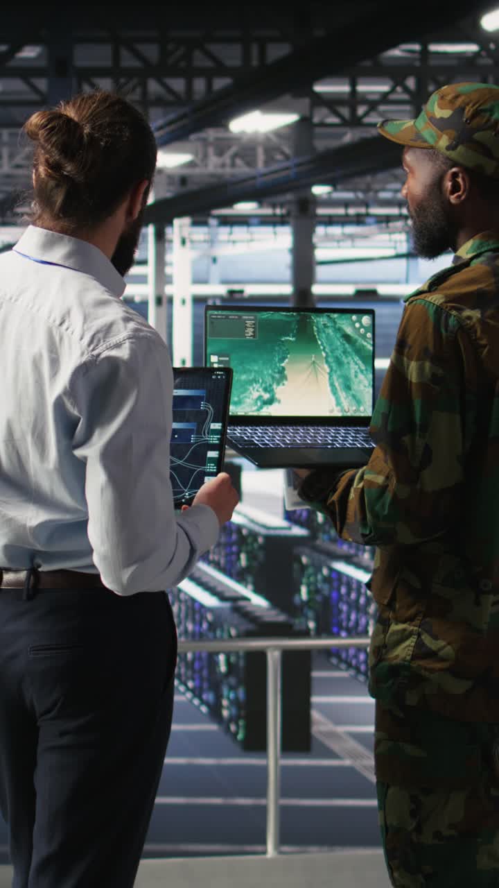 Vertical video Military experts in data center reviewing drone surveillance feed on laptop