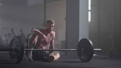 exhausted young men resting after intensive workout in gym. fitness healthy man tired after strength training exercise at gym. tired male fit model with standing and relaxing after intense workout.