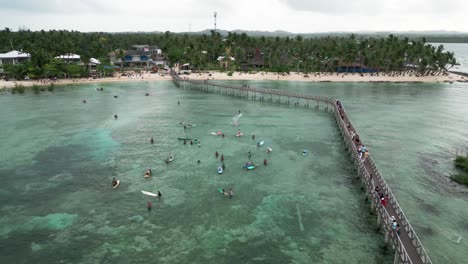 Drohnenaufnahme-Der-Holzpromenade-Von-Siargao-Und-Menschen-Beim-Surfen,-Philippinen