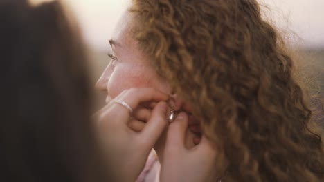 Young-woman-put-on-earrings-to-her-female-friend