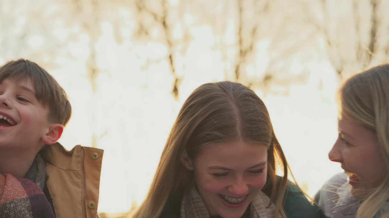 портрет семьи на прогулке по осенней сельской местности вместе против пылающего вечернего солнца - снят в замедленном режиме