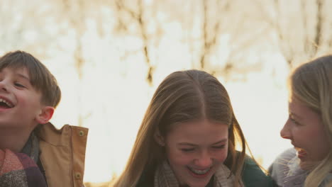 portrait of family on walk through autumn countryside together against flaring evening sun - shot in slow motion