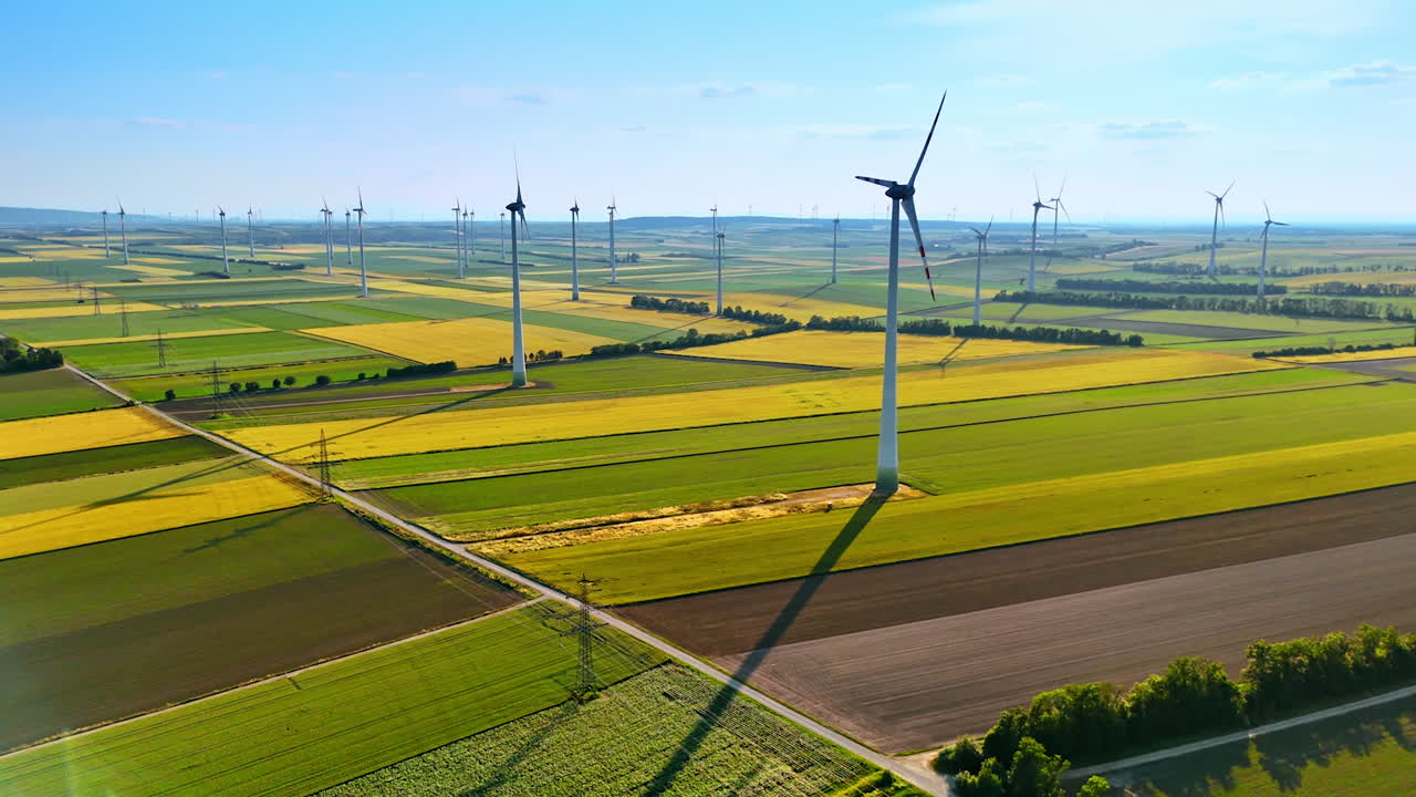 Blades of multiple windmills rotate slowly in the wind. Green energy production in the wind farms. Aerial view.