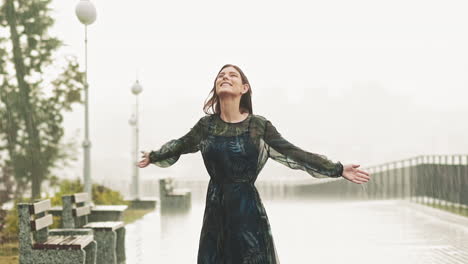 mujer positiva se encuentra bajo una fuerte lluvia en la cubierta de observación