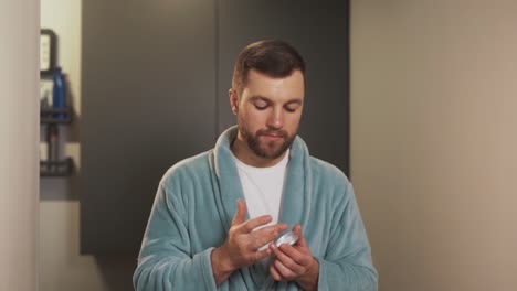 portrait of a well-groomed man applying face skin cream