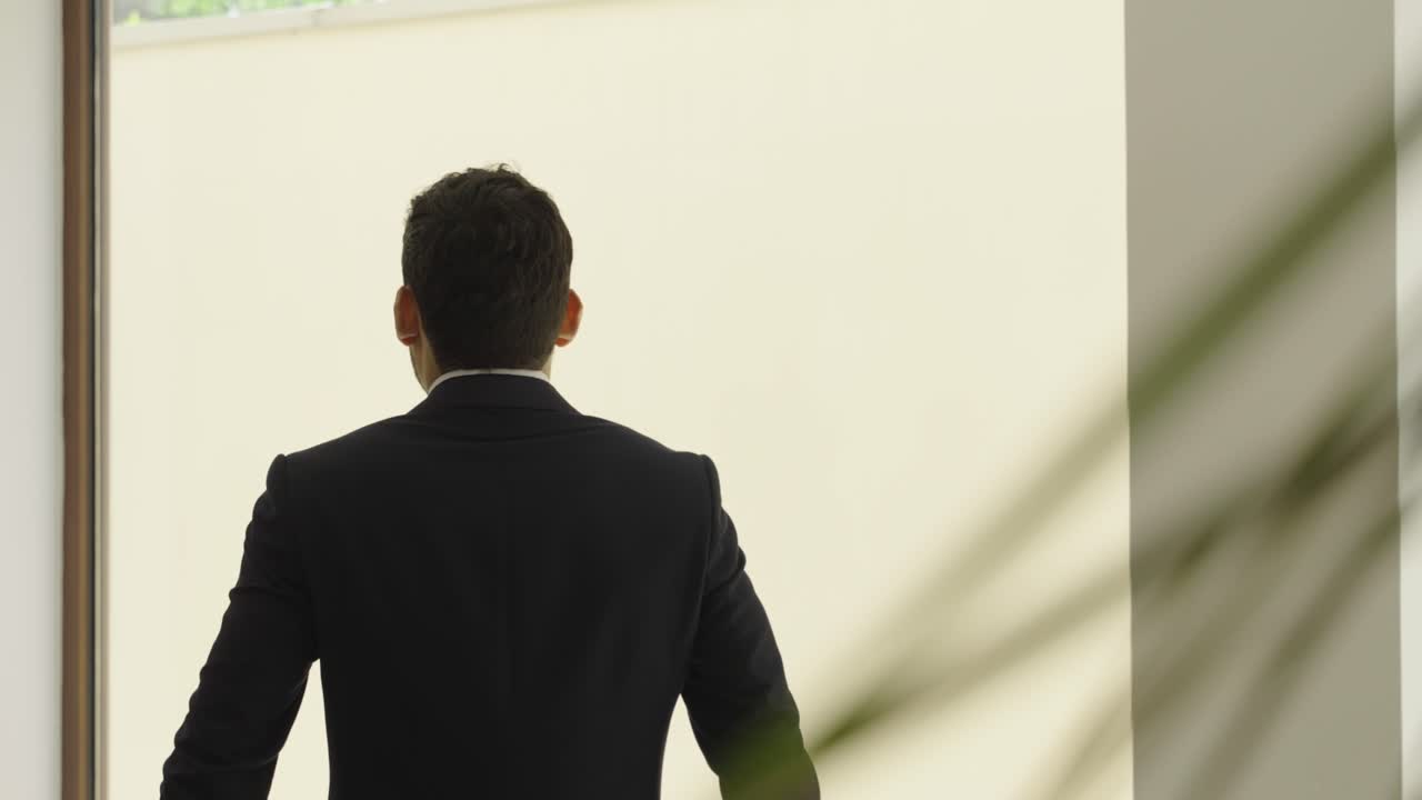 완전 한 슈트 를 입고 창문 밖 을 바라보는 남자 의 느린 움직임  ⁇