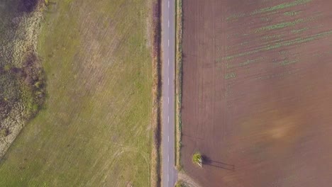 Flying-over-a-road-in-a-rural-with-a-few-cars-looking-down-from-a-drone