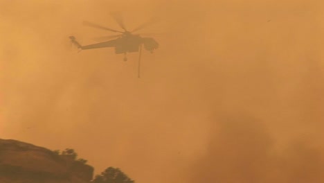 siguiente toma de un helicóptero arrojando productos químicos sobre un incendio forestal en california