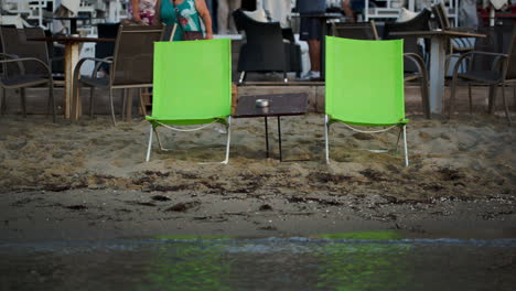 two empty chaise-lounges with table on the beach