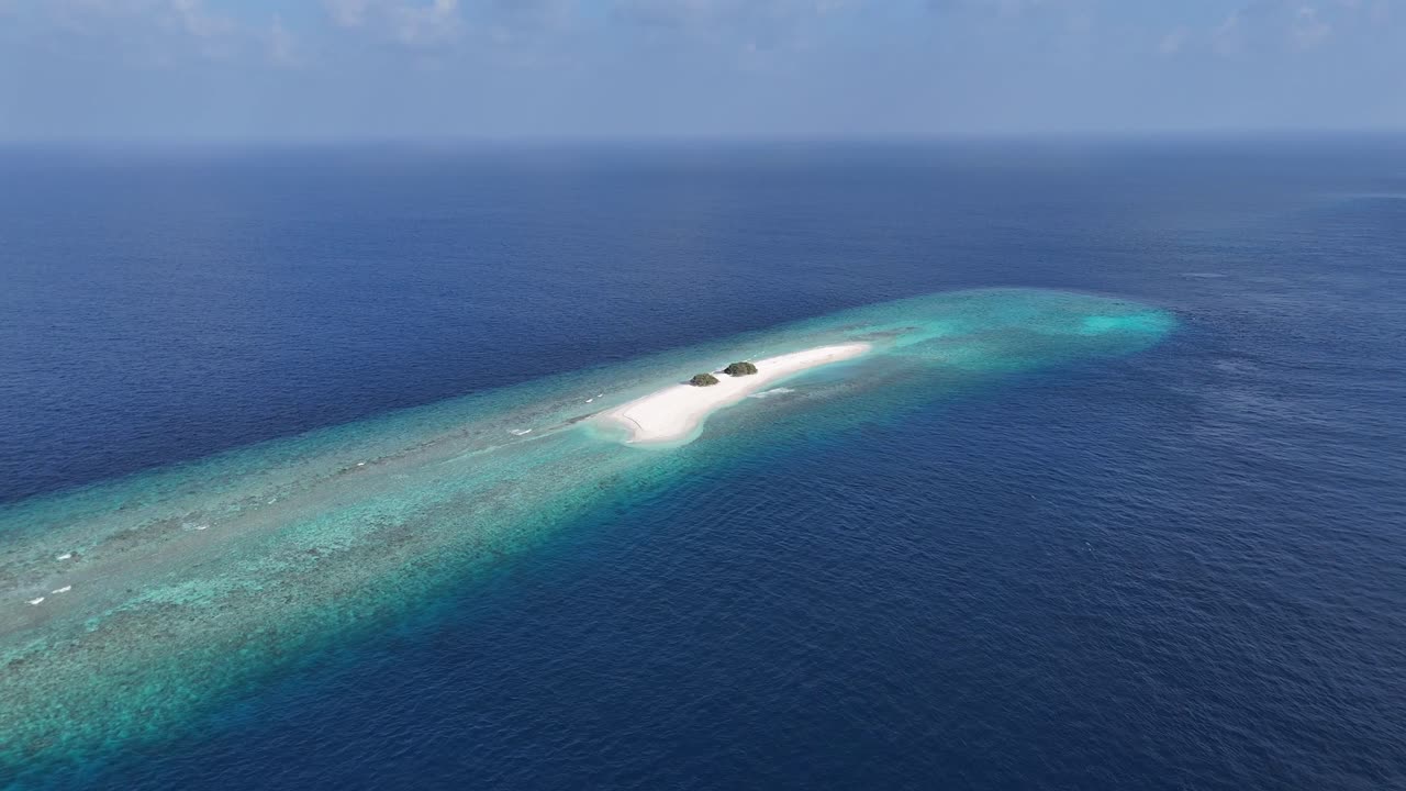 Vista aerea da drone di un'isola remota di sabbia alle Maldive, circondata da una laguna turchese