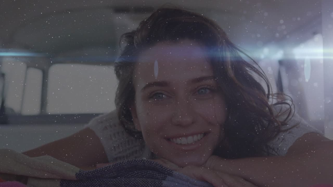 Woman resting in rear van for travel, sunlight causing lens flare and grain while smile easing