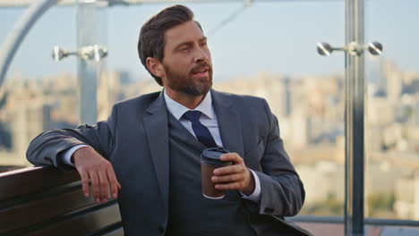 hombre exitoso disfrutando de café en la terraza de vidrio.