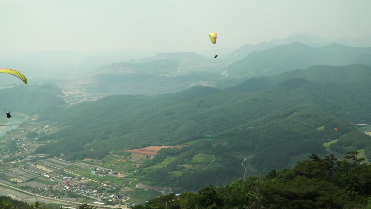 비가 내린 후 산이 증발할 때 한국 단양시의 산을 향해 날아가는 익스트림 패러글라이더, 4k 광각